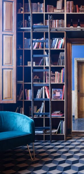 Een stijlvolle ruimte met een blauwe bank, boekenkast en houten ladder tegen een muur.