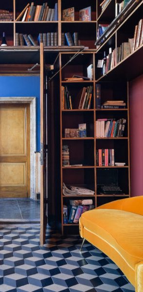 Interieur met boekenplank, gele bank en kleurrijke muren.