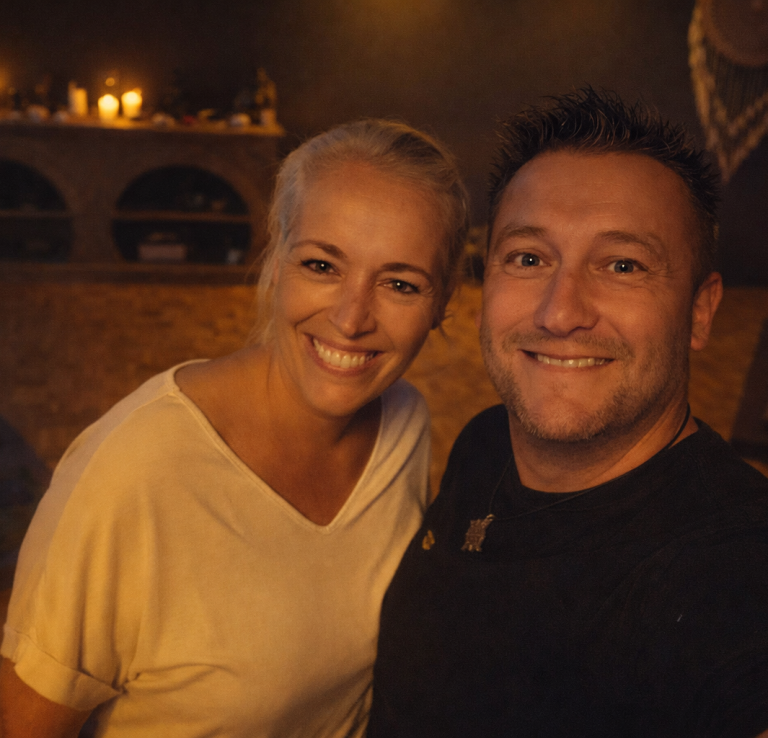 Twee vrolijke mensen poseren samen in een sfeervolle omgeving met gedimd licht voorafgaand aan sessie